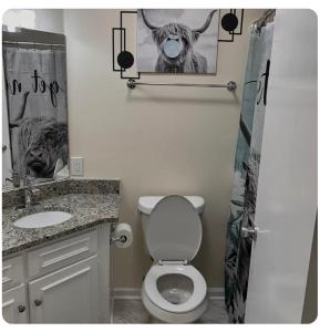 La salle de bains est pourvue de toilettes et d'une photo d'une vache. dans l'établissement Blue Ivey Estates - 5 miles from Ft. Moore, à Columbus