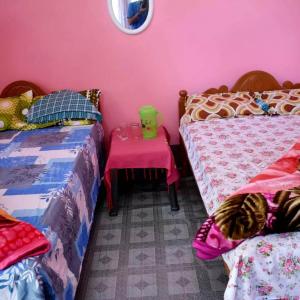 una camera con due letti e un tavolo con una parete rosa di Manas Ray Homestay a Jyoti Gaon