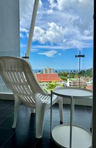 a white chair and a table on a balcony at Thawi Studio with Sea View in Chic Condo in Karon Beach