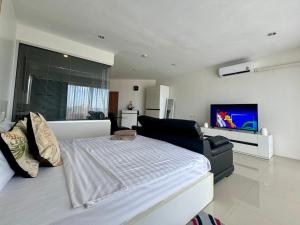 a bedroom with a large bed and a flat screen tv at Thawi Studio with Sea View in Chic Condo in Karon Beach