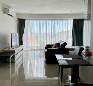 a person sitting on a couch in a living room at Thawi Studio with Sea View in Chic Condo in Karon Beach