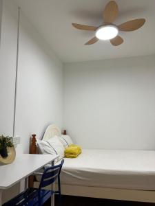 - une chambre avec un lit et un ventilateur de plafond dans l'établissement Duke Living, à Singapour