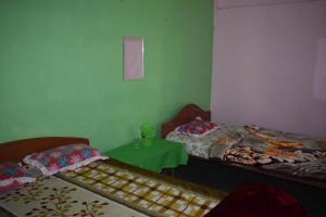 a room with two beds and a green table at Manas Ray Homestay in Jyoti Gaon