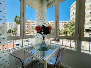 um vaso de flores numa mesa de vidro numa sala com janelas em Luxury loft with a pool in the centre em Torremolinos