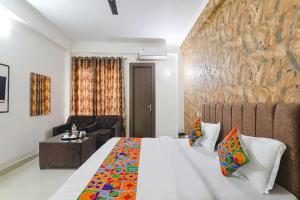 ein Hotelzimmer mit einem Bett, einem Stuhl und einem Tisch in der Unterkunft FabHotel The Villa I in Prayagraj