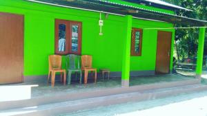 una casa verde con sillas delante en Manas Ray Homestay, en Jyoti Gaon