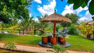a table with a straw umbrella in a park at Ceylon Amigos Eco Resort in Sigiriya