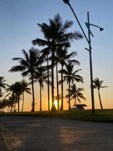 a street with palm trees and a sunset in the background at Pousada Poleto's in Bertioga