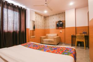 een slaapkamer met een bed, een stoel en een televisie bij FabHotel Ssensse in New Delhi