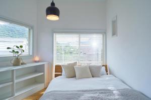 a white bedroom with a bed and a window at MORITO Funny house in Hayama