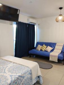 Monoambiente Tres Barrios في بوينس آيرس: غرفة معيشة مع أريكة زرقاء وتلفزيون