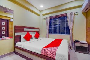 a bedroom with a bed with red pillows and a window at OYO Tranquil Stay in Ālīpur