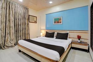 1 dormitorio con 1 cama grande y pared azul en Collection O Guru Heritage Kalamboli, en Bombay