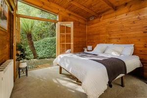 a bedroom with a bed and a large window at Modern Seednest Treehouse, Forest & Mountain View in Sassafras +26 photos
