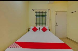 1 dormitorio con 1 cama blanca grande con almohadas rojas en OYO Flagship Hotel Diamond Palace, en Kumbalgod