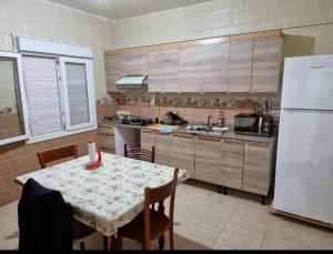 a kitchen with a table and a white refrigerator at Cité 200 logement lpp mimouni borj el Kiffan alger in Fort de lʼEau