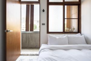 a bedroom with a bed with white sheets and a window at 軟寓 nńg inn in Tainan