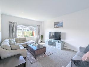 sala de estar con 2 sofás y TV en Beautiful Brand New Four-Bed Home near Redwood en Rotorua