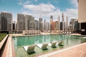a swimming pool with chairs and a city skyline at Primestay - 15 Northside 2BR in Business Bay in Dubai