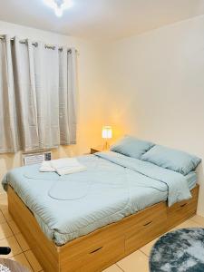 ein Schlafzimmer mit einem großen Bett mit blauer Bettwäsche in der Unterkunft New 8 Spatial Davao Smart Studio Unit Netflix Wi-Fi Amazon Voice Controlled Lights in Davao City