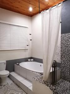 a bathroom with a bath tub and a toilet at Yield House and Cottages in Port Nolloth