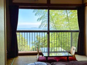 een kamer met een groot raam met een tafel en stoelen bij 123MUSIC(イズサンミュージック) in Atami