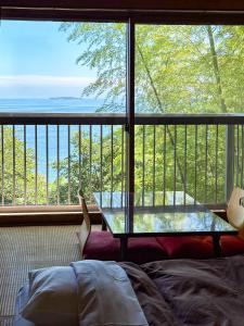 een kamer met een tafel en uitzicht op de oceaan bij 123MUSIC(イズサンミュージック) in Atami