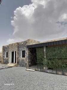 a stone building with a green wall at Cloud housing jabal shams in Sa‘ab Banī Khamīs