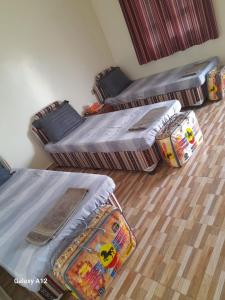 three beds and a couch in a room at Cloud housing jabal shams in Sa‘ab Banī Khamīs