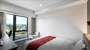 um quarto branco com uma cama e uma janela em Daiwa Roynet Hotel Fukuyama Ekimae em Fukuyama