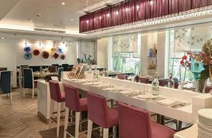 a restaurant with a long table and red chairs at The Ashtan Sarovar Portico in New Delhi