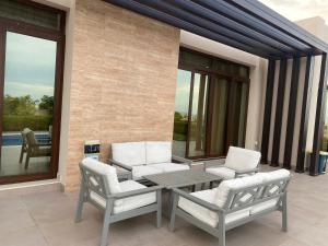 eine Terrasse mit 2 Stühlen, einem Tisch und Stühlen in der Unterkunft Beach front 2-bedroom villa Privat pool in As Sīfah