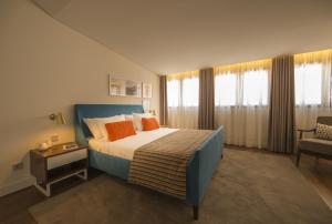 a bedroom with a large bed and a chair at Somewhere - Estoril Guesthouse in Estoril