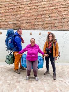 un grupo de tres personas de pie junto a una pared de ladrillo en BnB Royal Tourist House, en Katmandú