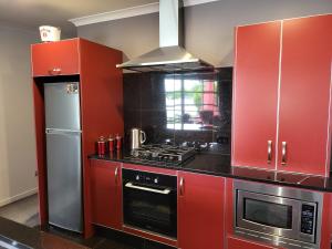cocina roja con fogones y nevera en De Vine Martinborough #26, en Martinborough