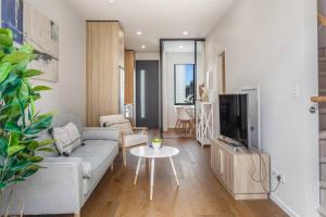 een woonkamer met een bank en een tv bij Fresh & sleek Grey Lynn unit with private patio in Auckland