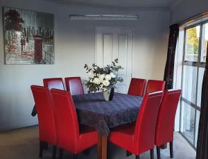 una mesa de comedor con sillas rojas y un jarrón de flores en De Vine Martinborough #26, en Martinborough