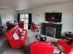 sala de estar con muebles de color rojo y TV de pantalla plana en De Vine Martinborough #26, en Martinborough