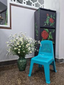 una silla azul junto a un jarrón con flores en May's Cottage, en Hanói