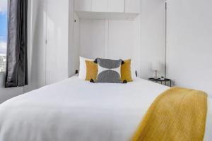 Dormitorio blanco con cama blanca y almohadas amarillas en KCM Mikros Smart Apartments 4, en Cleveland