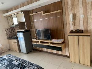 uma cozinha com frigorífico e uma televisão em OYO Life 93374 Andira Inn em Depok