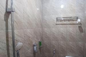 a shower in a bathroom with a tile wall at SPOT ON 93376 Roemah Ambarrukma 185 Syariah in Yogyakarta