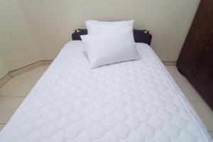 a white bed with a pillow on top of it at SPOT ON 93376 Roemah Ambarrukma 185 Syariah in Yogyakarta
