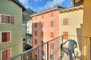 una silla sentada en un balcón con edificios en Casa Alpino - Happy Rentals, en Riva del Garda