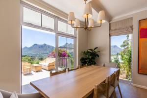 a dining room with a wooden table and a large window at Elite Retreats - Hillside Villa 2 - power backup in Cape Town