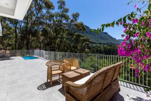 a patio with chairs and a fence and flowers at Elite Retreats - Hillside Villa 2 - power backup in Cape Town