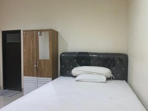 a bed with a black headboard in a room at OYO 93388 Enjoy Homestay & Cafe in Sungguminasa