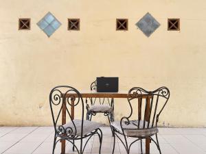 einem Holztisch mit zwei Stühlen und einem Laptop darauf in der Unterkunft SPOT ON 93398 Sudimoro Guest House Syariah in Blimbing