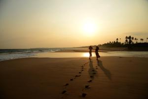 2 personnes marchant sur la plage au coucher du soleil dans l'établissement Back of beyond - Wellness Retreat, à Tangalle