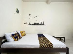 Schlafzimmer mit einem Bett mit gelben und blauen Kissen in der Unterkunft SPOT ON 93398 Sudimoro Guest House Syariah in Blimbing